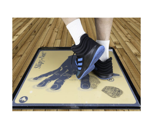 Athlete steps on adhesive sports traction mat to lift dirt from sneaker soles